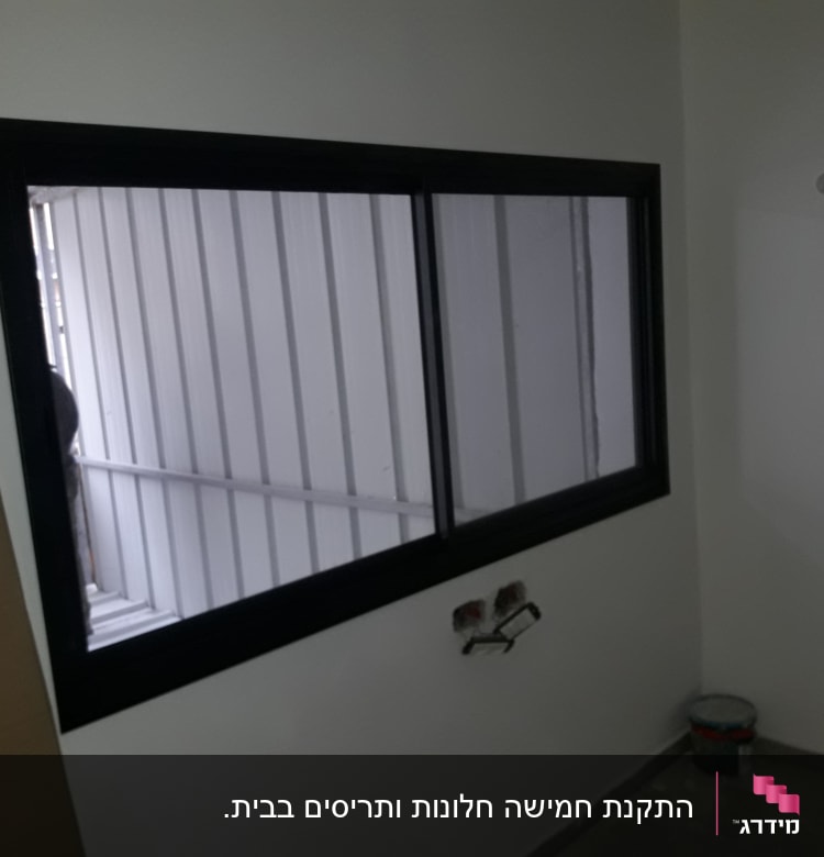 חלון אלומיניום עם מסגרת שחורה על קיר לבן